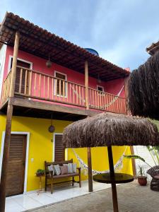 a yellow and red house with a balcony at Alto Mar Flats in São Miguel do Gostoso