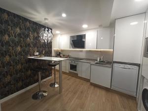 a kitchen with white cabinets and a table in it at Apartamento de Colón in Gijón