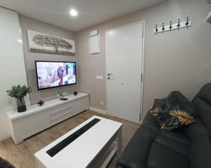 a living room with a couch and a flat screen tv at Apartamento de Colón in Gijón