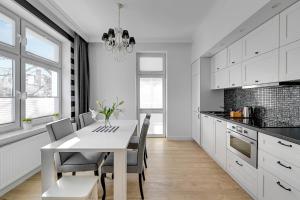 a white kitchen with a white table and chairs at Grand Apartments - Apartamenty Haffnera w samym sercu Sopotu in Sopot