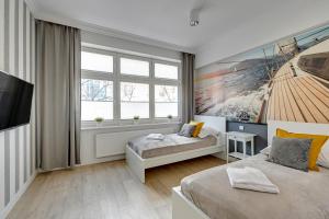 a bedroom with two beds and a large window at Grand Apartments - Apartamenty Haffnera w samym sercu Sopotu in Sopot