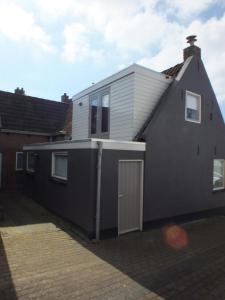uma casa cinzenta com uma porta ao lado em Stijlvol & lief onthaast-huisje, no wifi-tv em Holwerd