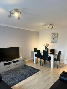 a living room with a table with chairs and a television at Spacious, modern 3 bedroom luxury flat in centre location in Broughty Ferry