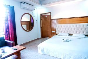 a bedroom with a large white bed and a mirror at Impulse Ocean View in Cox's Bazar
