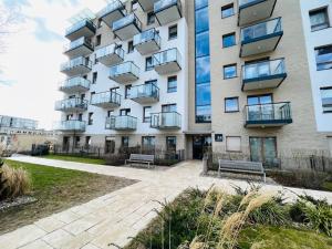 un edificio con dos bancos delante en Apartament Starowiejska 54, en Gdansk