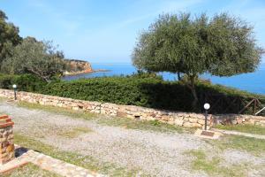 a stone wall with a tree next to the ocean at Rais Gerbi Appartamento in Pollina