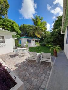 a patio with two chairs and a table in a yard at Kismet Garden Cottages - Dover Beach in Christ Church