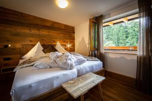 1 dormitorio con 1 cama con pared de madera y ventana en Brunnenhof Oberstdorf - Ferienwohnungen mit Hotel Service en Oberstdorf
