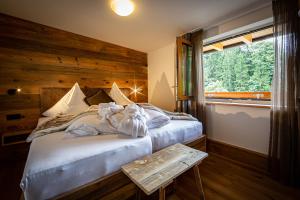 a bedroom with a bed with a wooden wall and a window at Brunnenhof Oberstdorf - Ferienwohnungen mit Hotel Service in Oberstdorf