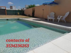 einen Pool mit einem Stuhl und einem Sonnenschirm in der Unterkunft CASA QUINTA La Donna con DESAYUNO in Villa María