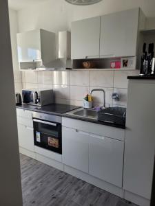 uma cozinha com armários brancos e um lavatório em Roko em Trogir