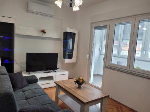 uma sala de estar com um sofá e uma televisão em Roko em Trogir