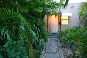 een huis met een loopbrug naar een voordeur bij 1BR Historic Art Deco Charm Meets Modern Comfort- Huge Tropical Garden in Posh Coral Gables-10 min Airport in Miami