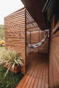 una terraza de madera con una hamaca. en Pousada Colina Verde en Garopaba