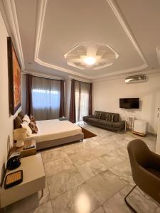 a bedroom with a bed and a couch and a tv at Francesca Guest House in Dakar