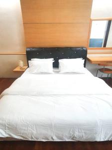 [HERITAGE 4] HOMESTAY Studio 4Pax, FREE WIFI في سيري كيمبانغان: غرفة نوم مع سرير أبيض مع اللوح الأمامي الأسود