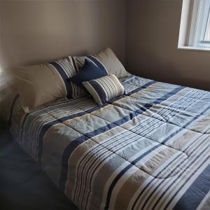 een bed met een blauwe en witte deken en kussens bij Quails Roost in Summerland