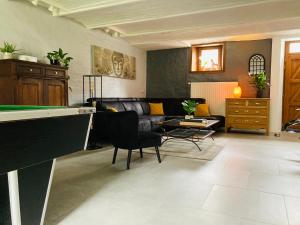 a living room with a couch and a pool table at Le chant de l Aisne in Érezée