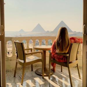 una mujer sentada en una mesa mirando las pirámides en Hi Pyramids, en El Cairo