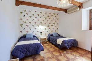 2 camas en una habitación con mariposas en la pared en Apartamentos La Solana de Monfragüe, en Malpartida de Plasencia