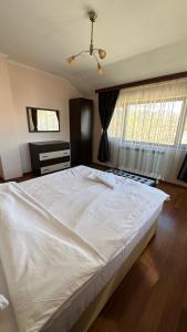 ein großes weißes Bett in einem Schlafzimmer mit Fenstern in der Unterkunft Valevitsata Guesthouse in Raslog