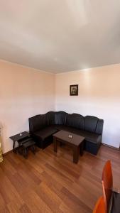 a living room with a black couch and a table at Valevitsata Guesthouse in Razlog