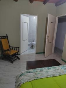 1 dormitorio con 1 cama y 1 silla y baño en La Casona de Cerro Colonial, en Trapiche 6 fotos más