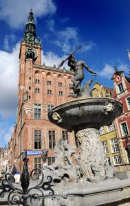 a statue of a man on a fountain in front of a building at Hotel Artus - Old Town in Gdańsk