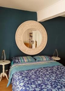 a bedroom with a bed and a round mirror at Chambre d'hôtes Les Myriades D'Or in Regny