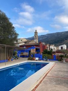 a swimming pool in front of a building with a clock tower at Casa Gallinera in Benissiva