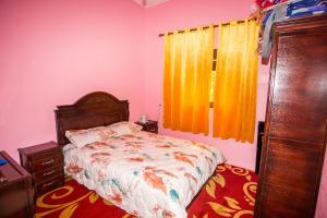 a bedroom with a bed and a window with yellow curtains at La belle vue in Daher