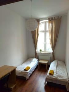 two beds in a room with a desk and a window at Apartament Parkowy in Kętrzyn