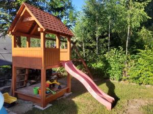 a wooden play tower with a slide in a yard at Chalupa pod Lysou in Rokytnice nad Jizerou