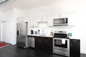 a kitchen with stainless steel appliances and black cabinets at Flexhome Skywalk to Fiserv 1BR Apt U6 - READ INFO in Milwaukee