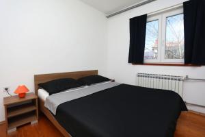 een slaapkamer met een zwart-wit bed en een raam bij Apartment Rozman in Vozilići