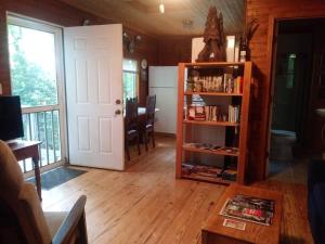 a living room with a book shelf and a door at Two Rivers Cabins - The Dell in Brevard