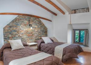 um quarto com 2 camas e uma parede de tijolos em Apartamentos La Solana de Monfragüe em Malpartida de Plasencia