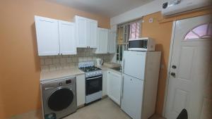 a kitchen with white cabinets and a stove and a refrigerator at 2 minutes from Roseau, Cozy studio with shared pool in Roseau