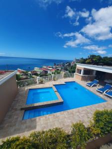 a swimming pool on the roof of a house with the ocean at 2 minutes from Roseau, Cozy studio with shared pool in Roseau
