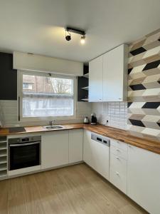 uma cozinha com armários brancos e uma janela em L'Ocenoa2 em Mimizan