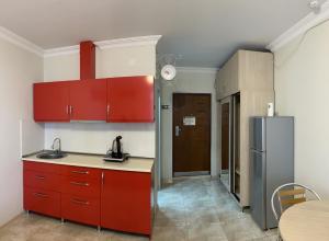 Orbi apartamenti batumi 15 b في باتومي: مطبخ مع دواليب حمراء وطاولة وثلاجة