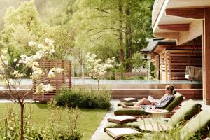 a woman sitting on a couch in a garden at MalisGarten Green Spa Hotel in Zell am Ziller