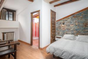 een slaapkamer met een bed en een bakstenen muur bij Apartamentos La Solana de Monfragüe in Malpartida de Plasencia