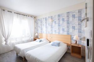 2 camas en una habitación de hotel con ventana en Hotel Les Rocailles, en Montagnac
