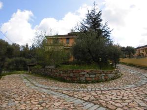 uma estrada de pedra com uma parede de pedra em frente a uma casa em Casa vacanze Villa Lucheria Loceri em Loceri