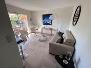 a living room with a couch and a table at Appartement avec terrasse, vue jardin et piscine in Antibes