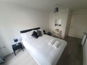 a bedroom with a white bed with two pillows on it at 2 bedroom light, spacious aptmnt nr Heathrow in Cranford