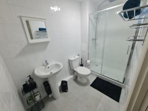 2 bedroom light, spacious aptmnt nr Heathrow في Cranford: حمام ابيض مع مرحاض ومغسلة