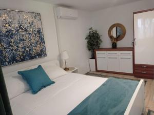- une chambre avec un lit blanc et un oreiller bleu dans l'établissement Apartments Bride's Rock, à Baška Voda