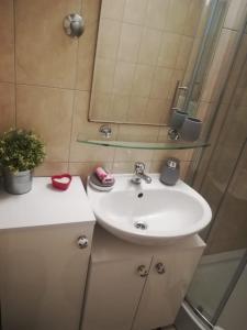 La salle de bains est pourvue d'un lavabo blanc et d'un miroir. dans l'établissement Apartments Bride's Rock, à Baška Voda